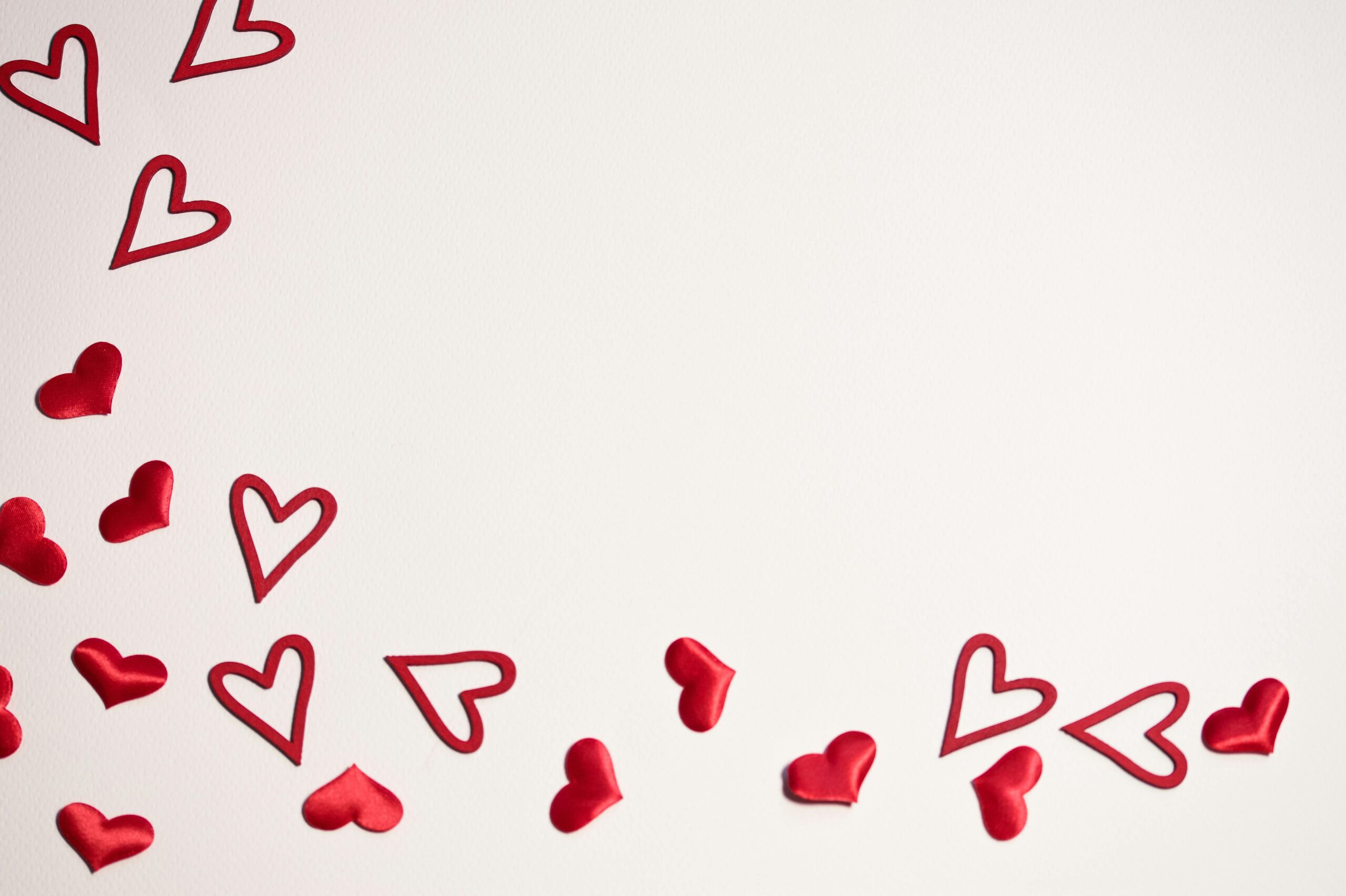 Red hearts scattered on a white background, ideal for Valentine's Day or romantic themes.