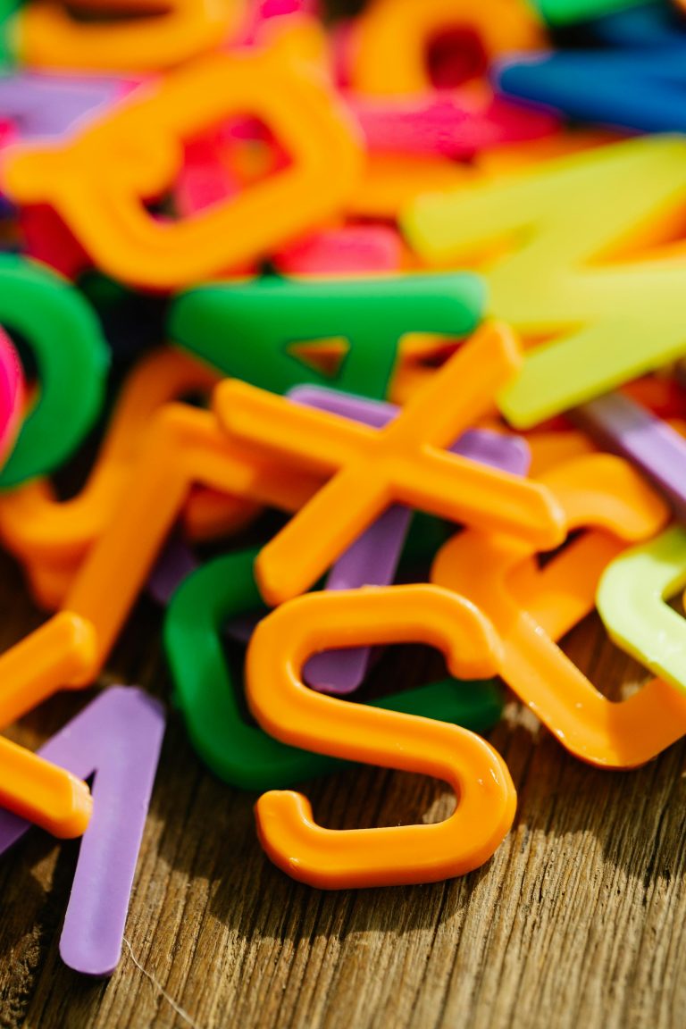 Bright plastic alphabet letters scattered on a wooden table, perfect for educational themes.